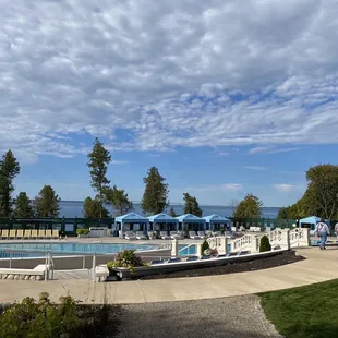 an outdoor pool with lounge chairs and umbrellas