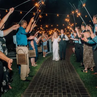 a bride and groom walking down the aisle with sparklers