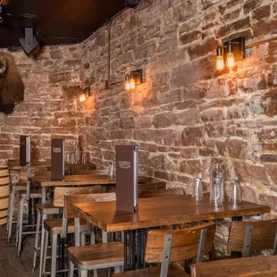 tables and stools in front of a brick wall