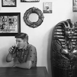 a man sitting at a table in front of an egyptian statue