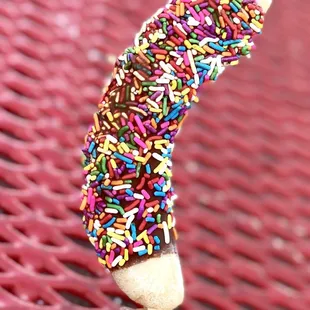 a hand holding a donut covered in sprinkles