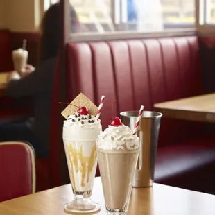 two sundaes with whipped cream and a cherry on top