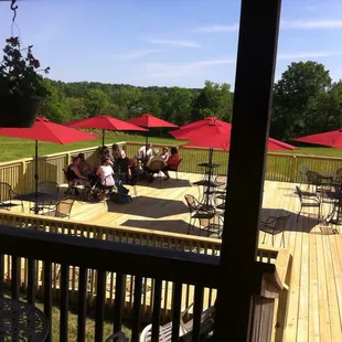 a group of people sitting on a deck with red umbrellas