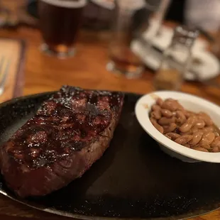steak and beans on a black plate