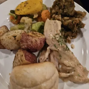 Turkey, stuffing, roasted potatoes, warm roll, and mixed veggies.