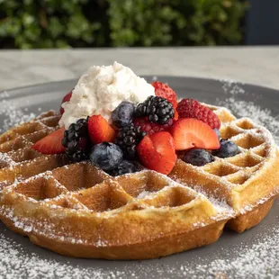 Waffles topped with powdered sugar and fruit
