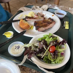 Pork ribs, salad with blue cheese dressing and potato salad.
