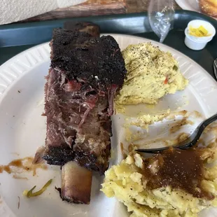 Beef rib with potato salad and mashed potatoes with brown gravy.
