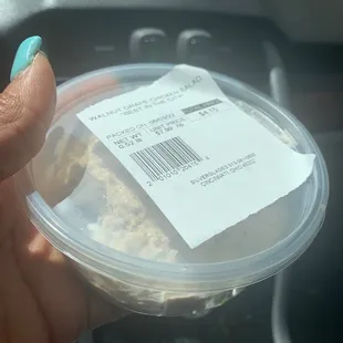 a hand holding a plastic container of food