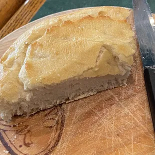 a piece of bread on a cutting board with a knife