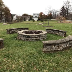 Concrete fire pit with concrete cornhole game in the background