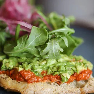 a plate with a sandwich topped with guacamole and lettuce