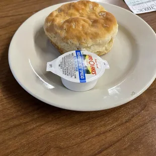 a biscuit on a plate with a cup of yogurt