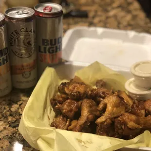 a tray of chicken wings and a can of bud light
