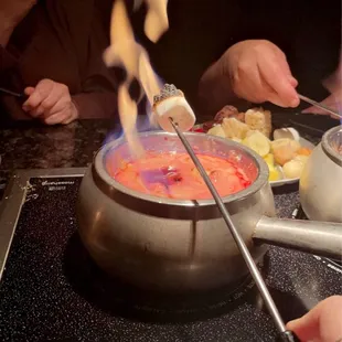 a person using tongs to make a fondini