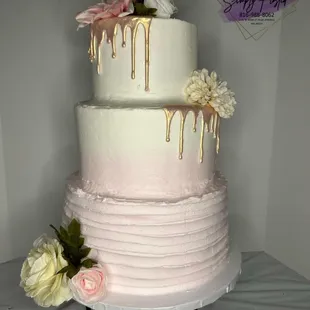 a three tiered cake with drips and flowers