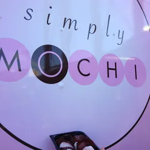 a hand holding a box of doughnuts