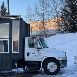 a pizza truck parked in the snow