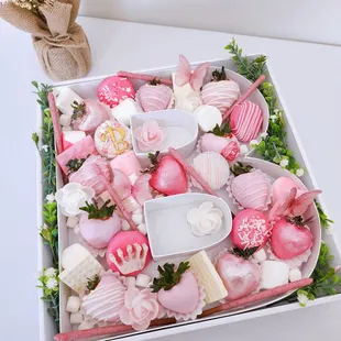 Chocolate-covered treat box with strawberries, candy, and cookies. Name initial inspired gift box in shades of pink.