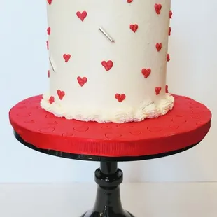 Delicious 3-layer vanilla Sweet Hearts Cake decorated with red hearts, red adornments and highlights in silver.