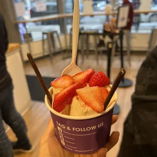Strawberry pieces in vanilla ice cream with chocolate pocky on top.