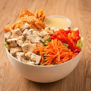 chicken, carrots, lettuce, carrots, and pickles in a bowl