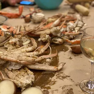 crab legs on a table with a glass of wine