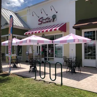 the outside of a store with tables and umbrellas