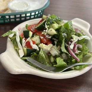 a plate of salad and a basket of bread