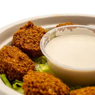 a plate of fried chicken nuggies with a dipping sauce