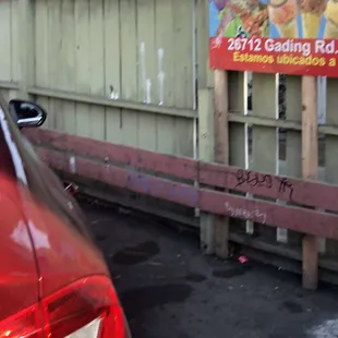 a red car parked in front of a fence