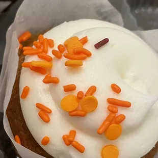 a cupcake with white frosting and orange sprinkles