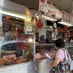a woman standing in front of a meat display