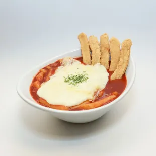 a bowl of tomato soup with breadsticks