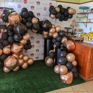 a balloon arch made of black and copper balloons