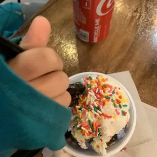 a hand holding a cupcake with sprinkles