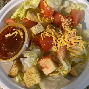 a plate of salad with dressing and croutons