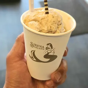 a hand holding a cup of gelato