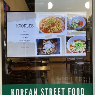 a menu displayed in a window of a korean street food restaurant
