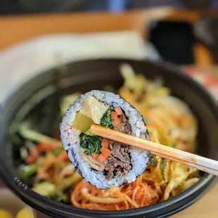 a person holding chopsticks over a bowl of food