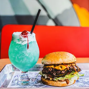 a burger and a drink on a tray
