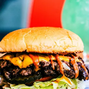 a hamburger with lettuce, cheese, and sauce