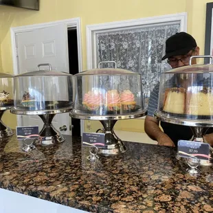 a man behind a counter with cakes