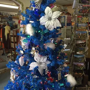 Blue Christmas tree decorated with white and silver ornament for sale.