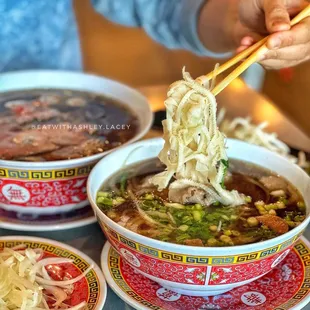 a person holding chopsticks over a bowl of soup