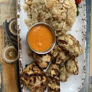 Chicken kabob with rice pilaf and hot sauce