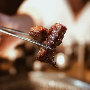 a close up of a person holding a pair of tongs