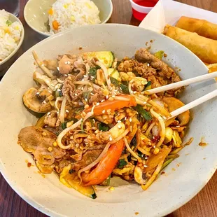 a bowl of stir fried noodles with chopsticks