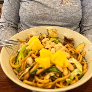 a woman holding a bowl of noodles