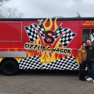 a man and a woman standing in front of a food truck